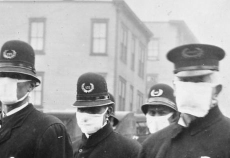 A dozen police officers stand in the street wearing heavy winter coats and masks.