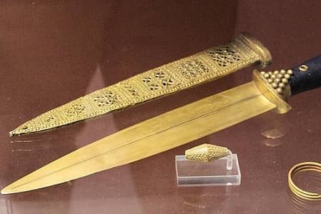 A knife made of gold. Next to it is its sheath, delicately carved, also in gold.