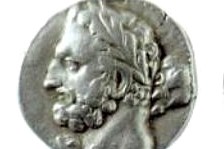 A silver coin with the face of a bearded man. He has a laurel wreath on his head, like a Greek king.