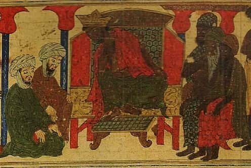 An African king sits on a throne and wears a crown. He is surrounded by his countrymen. All have dark skin, wear skirts, and have the torso uncovered. Two bearded men of white skin kneel next to the king. They wear turbans and robes.