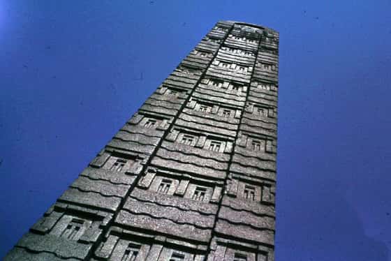 Tall square obelisk made out of gray stone. It is carved with decorations.