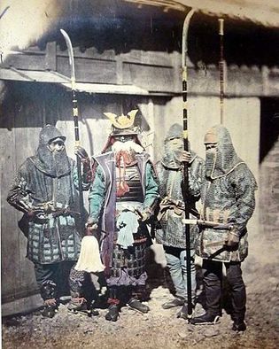 Photo. Four men in full samurai armor stand in front of a house.
