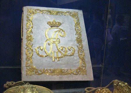 A book with a beautifully decorated cover is displayed in a museum.