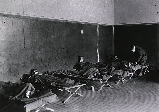 Interior of a room that has beds and soldiers lying on them.