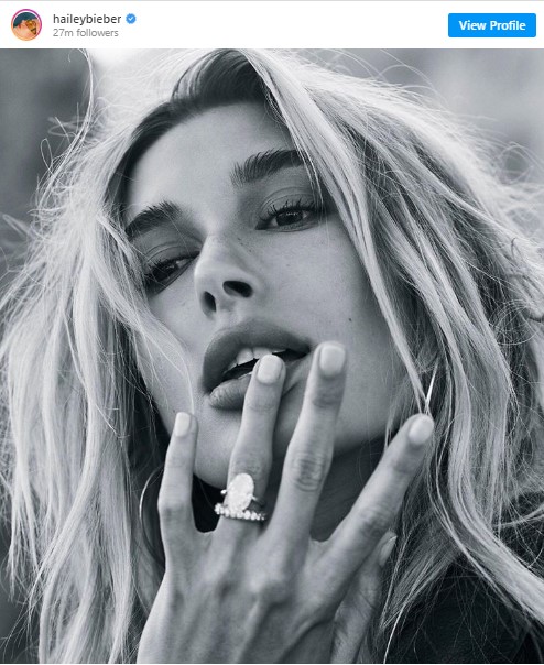 Black and white picture of Hailey. It is a close-up. Hailey touches her lips with her ring finger which sports a big diamond ring.
