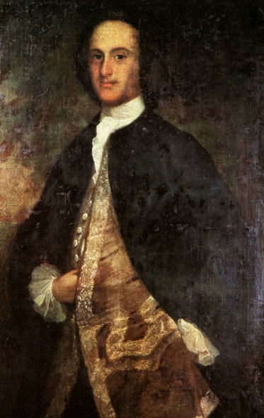 A man elegantly dressed in the European style of the 18th century. His hair is dark. His face is thinn-ish and long, his nose prominent, his forehead big, and his eyes are kind
