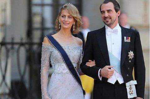 Tatiana and Nicolas in formal dress. He is in a tuxedo, she is in a long shiny dress. Both wear the royal sash and Tatiana wears a diamond crown.