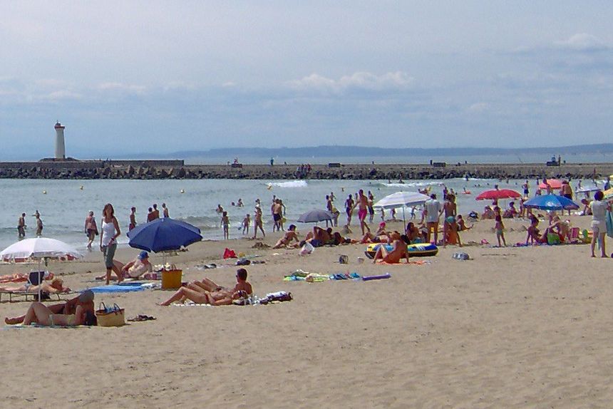 A somewhat crowded beach pictured from the ground. Some of the people are naked.