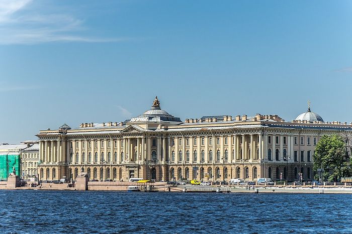A large neoclassical building three storeys high seen from across a river.