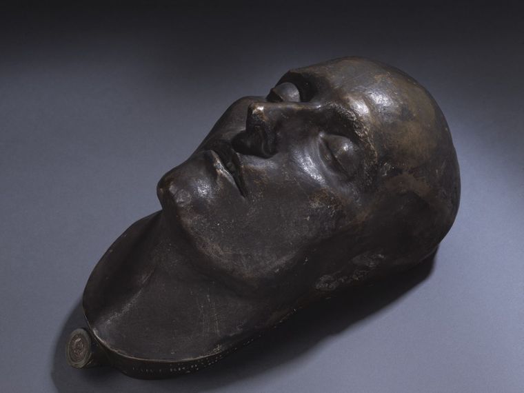 Bronze death mask of a historical figure. 3/4 view. Napoleon's face is somewhat thin from illness. He has harmonious features; a long, thin, aquiline nose; thin lips, biggish closed eyes, and a strong yet narrow chin.