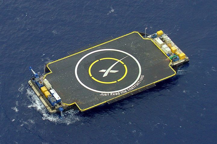 Picture of a landing pad, looks like a small aircraft carrier, and it is floating in the ocean. It has a big target drawn in the middle and below it, it says in big letters: "Just read the instructions."