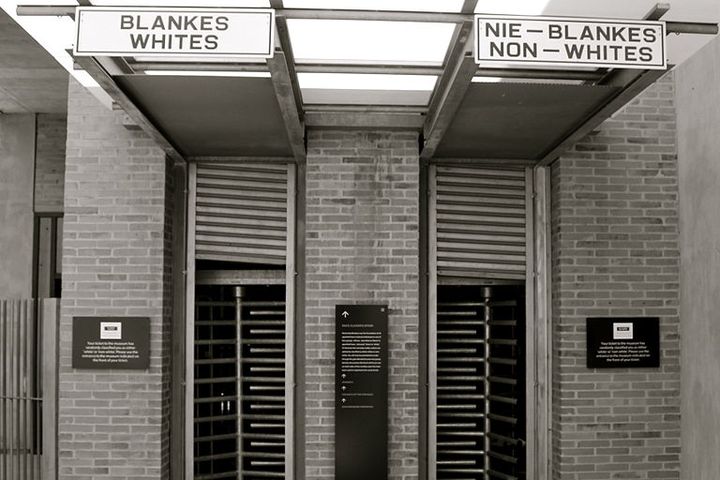 Picture of a building. It has two entrances, one is labeled "Whites", the other "Non-Whites."