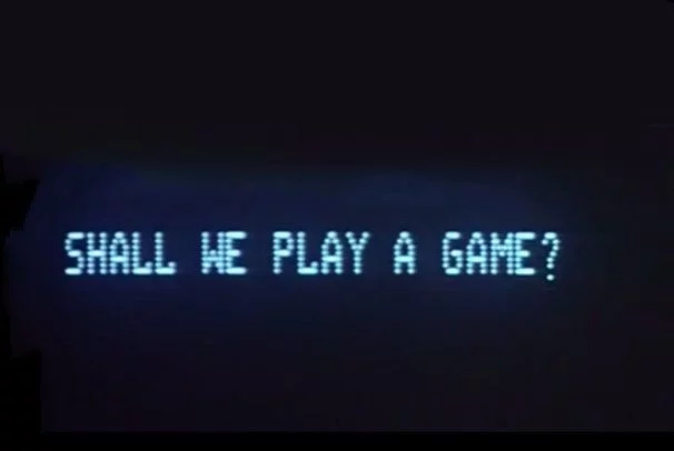 Picture of a black computer screen. It has written line in blue, which reads: "Shall we play a game?"