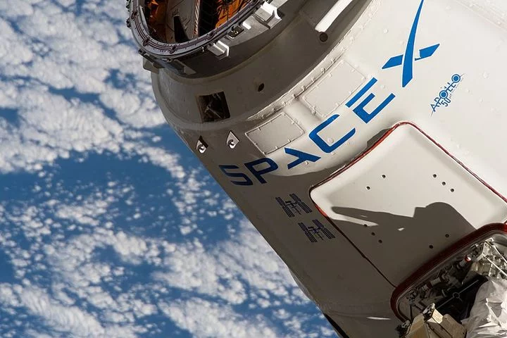 Picture of a SpaceX spacecraft floating in space with the Earth behind it. SpaceX is one of Elon Musk's companies.