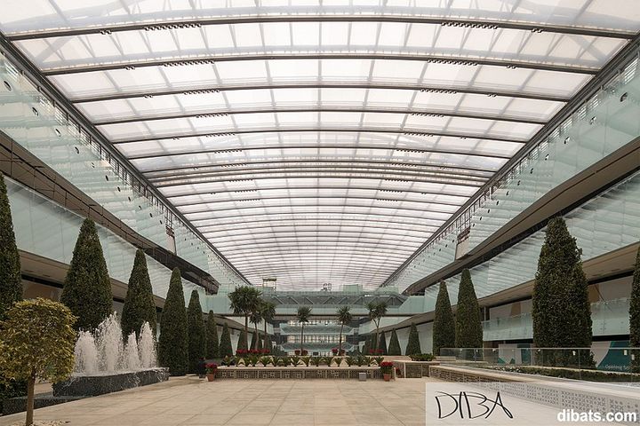 Inside a large empty, modern mall. It has a glass ceiling.