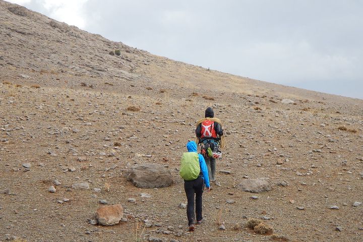 Two hikers, a man and a woman, walk up a deserted hill.