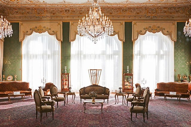 Inside a big room with Persian carpeting and European-style palatial furniture.