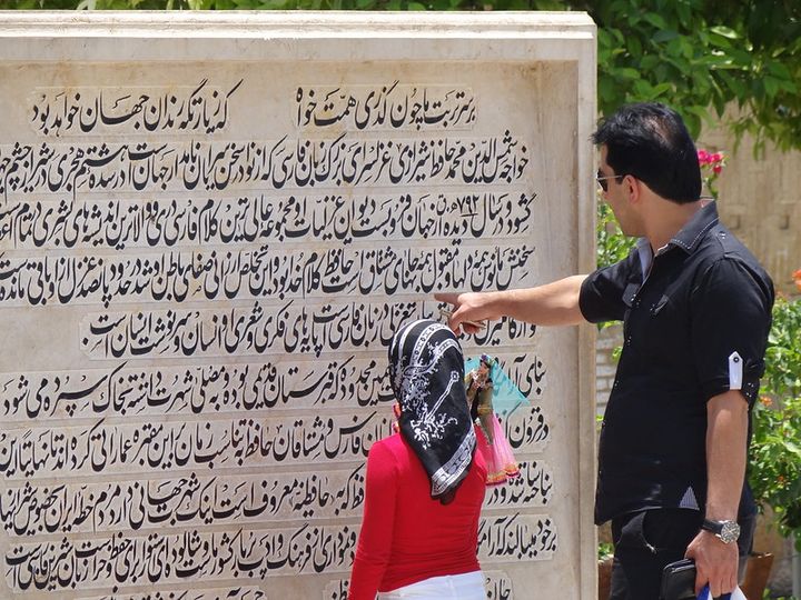 A father shows his young daughter an inscription on a wall.