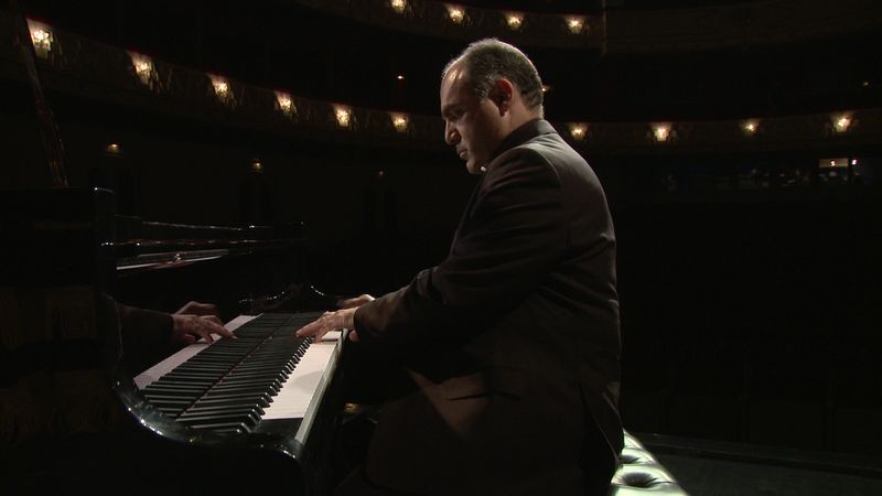 A man playing piano on stage during a concert