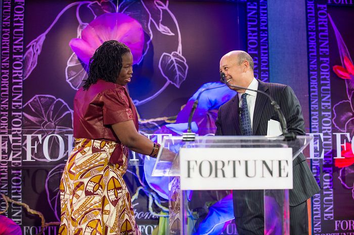 A woman shakes hand with a man on stage behind a podium. On the podium, it reads "Fortune."