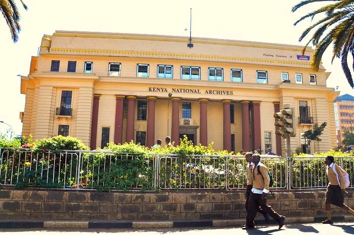 Big yellow European building with magenta columns. It is the Kenya National Archives.