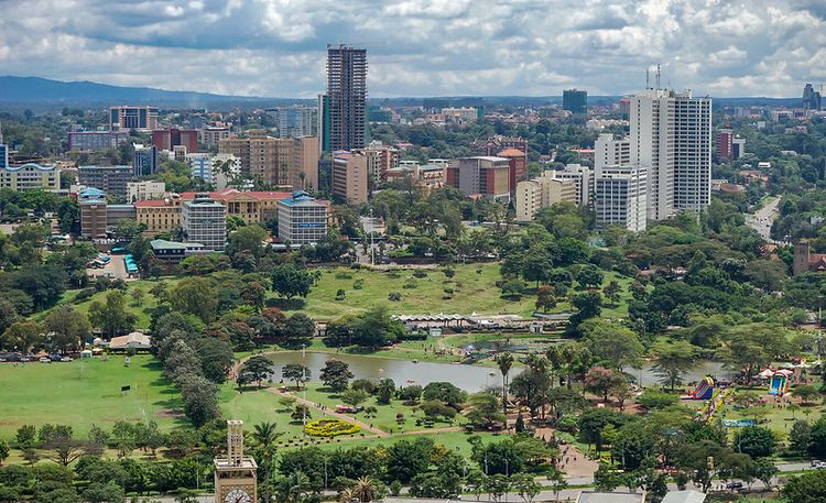 Aerial view of Nairobi. There is a very large park with a lake and trees in the foreground.