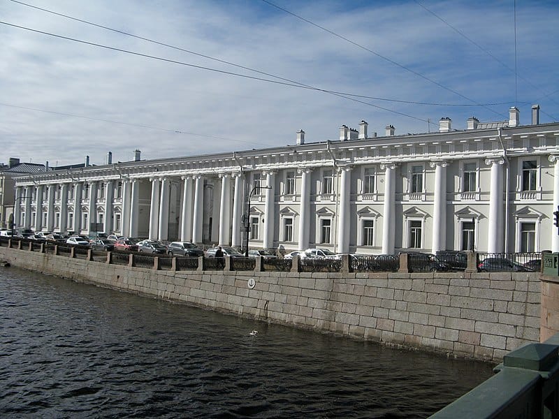 A wide large palace on the banks of a river.