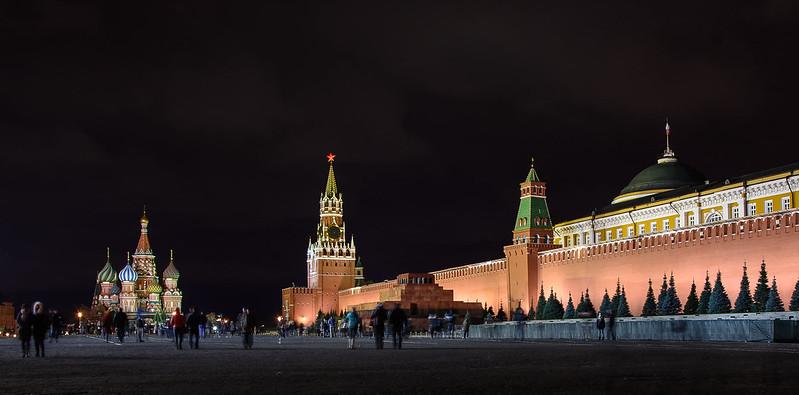 Night shot of the Red Square in Moscow. There is a church on the left and a big, red wall on the right.