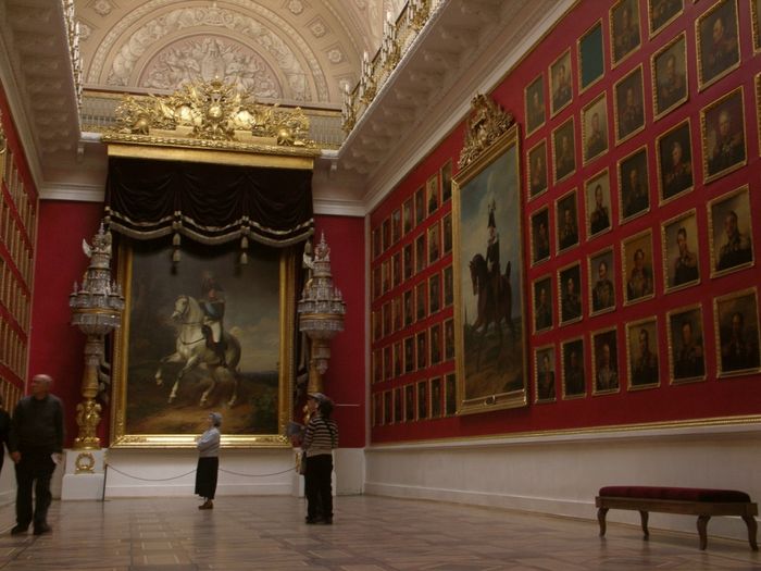 The interior of a museum with many paintings on the wall.