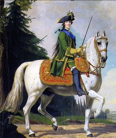 A middle-aged woman on a white horse riding astride. She wears man's clothes.