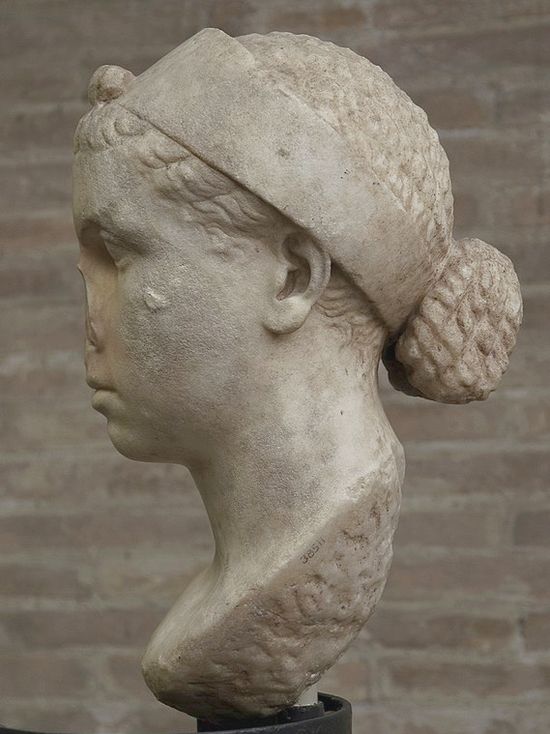 Marble bust of a pretty girl seen from the side. She wears a wide band on her head.