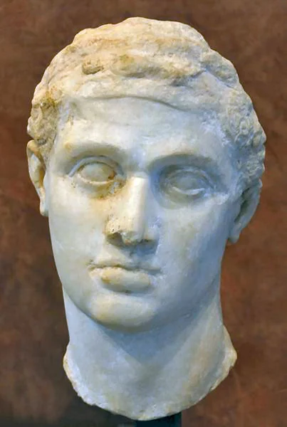 White marble head of a young man, an Hellenistic king with his headband. He has curved eyebrows, deep-set, big eyes; a big nose, fleshy lips, a rounded chin. His face is oval.