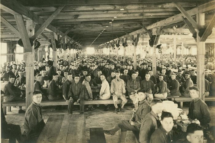 A crowded hall with at least 1000 soldiers sitting down to eat.